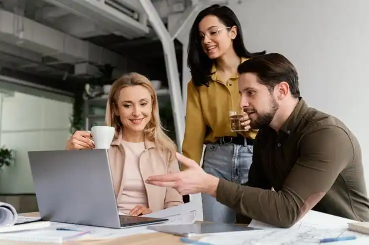 Small business team reviewing plans and funding options together around a laptop